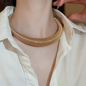 Detailed close-up of a chunky golden spiral snake chain necklace on a model's neck