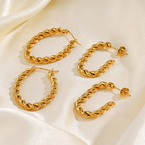 Boucles d'oreilles torsadées en acier inoxydable doré sur tissu en soie crème