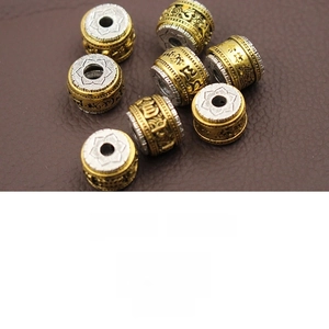 Macro detail of rotating alloy mantra bead with gold and silver finish and lotus engraving