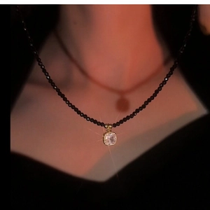 Vue détaillée d'un élégant collier de perles noires avec un pendentif en cristal carré.