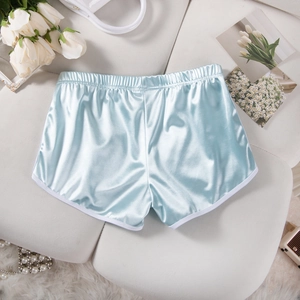 Close-up of light blue satin yoga shorts with white trim on a decorative sofa surface