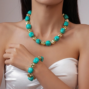 Detail of turquoise and gold geometric bead necklace and bracelet set on a model