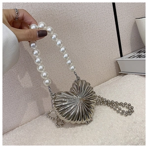 Close-up of heart-shaped silver metal box bag with pearl handle and beaded chain