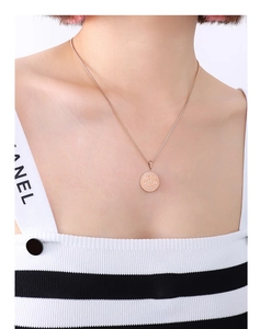Close-up of a rose gold coin necklace with Libra scales pendant worn by a model