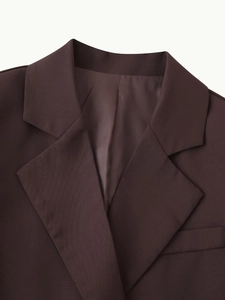 Detail shot of notched lapel on a dark brown blazer featuring premium fabric texture