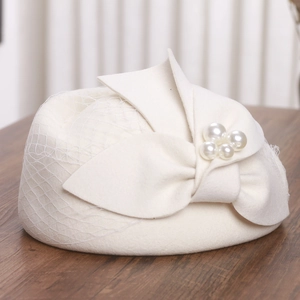 Detail of white wool pillbox hat with mesh veil, felt bow and pearl embellishments