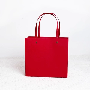 Elegant red gift paper bag with sturdy carry handles and premium gold rivet accents