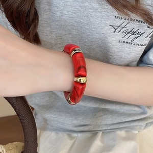 Macro detail of tortoiseshell acetate elastic bracelet with gold metallic accents on wrist