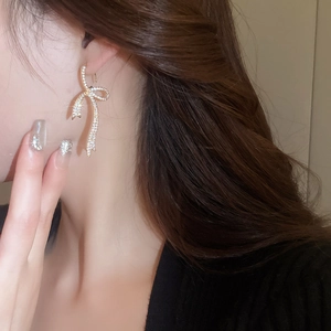 Close-up of sparkling gold bow earrings with cubic zirconia on a model's ear