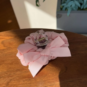 Close-up of pink lace bow hair claw clip on brown wooden background with soft lighting