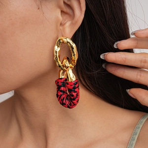 Detail of chunky gold earrings with red and black leopard print leather texture
