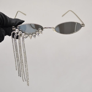 Oval silver sunglasses with sparkling crystal fringe and grey lenses on grey background