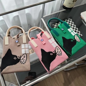 Mini sacs tricotés motif panda en beige, rose et vert sur une étagère en verre