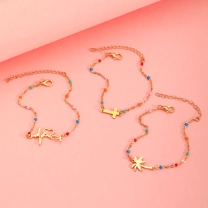 Close-up of gold plated bracelets with colorful beads, heart and palm tree charms