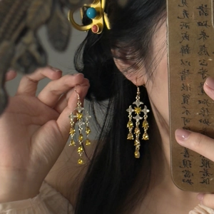 Detail of vintage gold tassel earrings with crystals on a model in an artistic retro setting