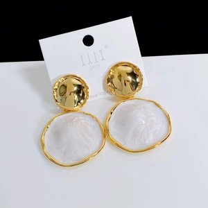 Detail of vintage round hammered metal earrings with white marble resin drop and silver post