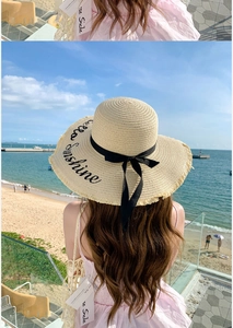 Detail of beige straw sun hat with Hello Sunshine embroidery and black ribbon bow