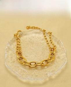 Detailed close-up of golden stainless steel thick chain link bracelet on glass tray