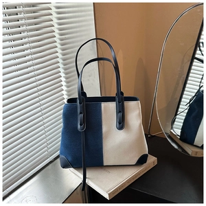 Detail view of large denim tote bag with blue and white patchwork and leather straps