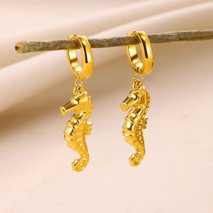 Vue détaillée de boucles d'oreilles hippocampe dorées suspendues à une branche en bois