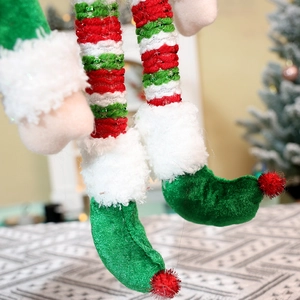 Details von Pailletten-Elfenschuhen und gestrickten Beinen für Weihnachtsdekorationen