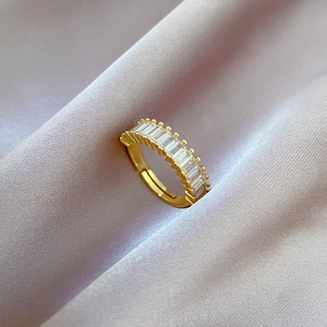 Detail of gold geometric open ring with rectangular white zircons on purple silk