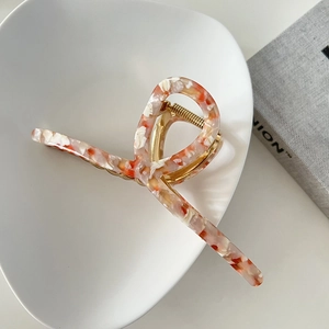 Detail of 13cm oversized marble orange acetate hair claw clip on minimalist ceramic tray