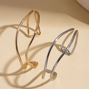 Minimalist geometric double-layered gold and silver wave bangles in artistic lighting