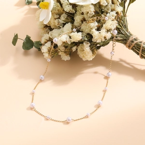 Detailed view of elegant gold pearl choker necklace with dried flower background