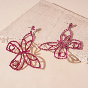 Detail shot of sparkling pink rhinestone butterfly earrings on a textured stone display