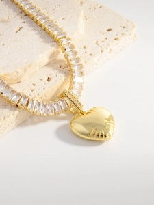 Detail of gold heart pendant with radial textures and cubic zirconia link chain