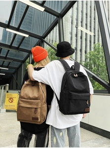Detailed back view of khaki and black canvas backpacks with vintage leather zipper pullers