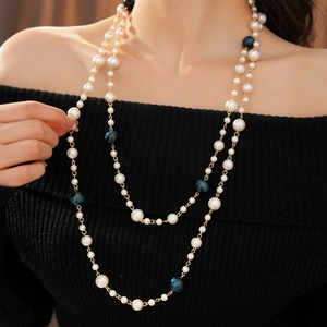 Detail of layered pearl necklace with tiger eye beads worn over a black sweater