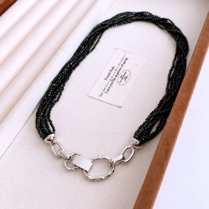 Détail du collier multirangs en perles noires avec fermoir argenté irrégulier