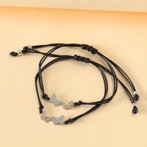 Paire de bracelets papillon noirs réglables avec breloques en acier sur fond pêche doux