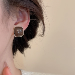 Close-up of minimalist square brown enamel earrings with silver needle on model ear