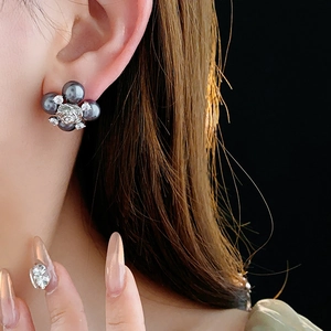 Detail of silver floral earrings with dark pearls and zircon stones on a model