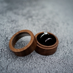 Macro shot of walnut wood ring box with velvet interior holding two wedding rings