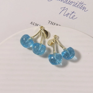 Close-up of two blue glitter resin cherry charms with golden metal stems and loops