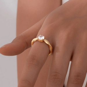 Close-up of gold Mobius ring with a single zircon on hand, minimalist jewelry detail