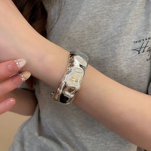 Detailed view of wide silver open cuff bracelet with irregular liquid metal texture on wrist