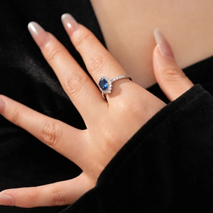 Close-up of open ring with hollow diamond flower design and oval blue zircon gemstone