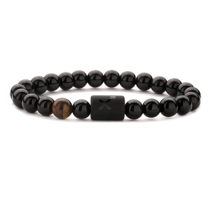 Close-up of black bead bracelet featuring tiger eye stone and Sagittarius symbol cylinder
