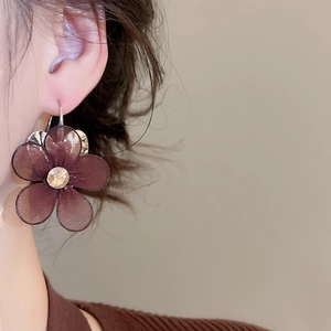 Close-up of a model wearing dark brown mesh flower earrings with central rhinestone accents