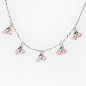 Detailed view of silver cherry necklace with pink cat eye stone and green zircon charms