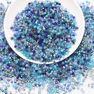 Detailed top view of mixed blue square glass beads in a white bowl for DIY jewelry