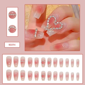 Detail of pink gradient press-on nails with sparkling rhinestones and heart decorations