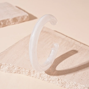 Detailed view of white translucent acrylic cuff bracelet on a minimalist stone base