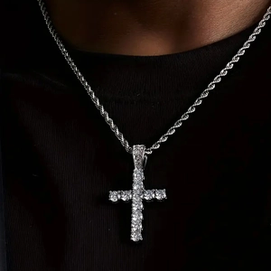 Close-up of a silver cross pendant with pavé crystals on a twisted rope chain necklace