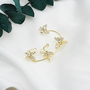 Detail of gold butterfly ear cuff with sparkling crystals on white draped fabric